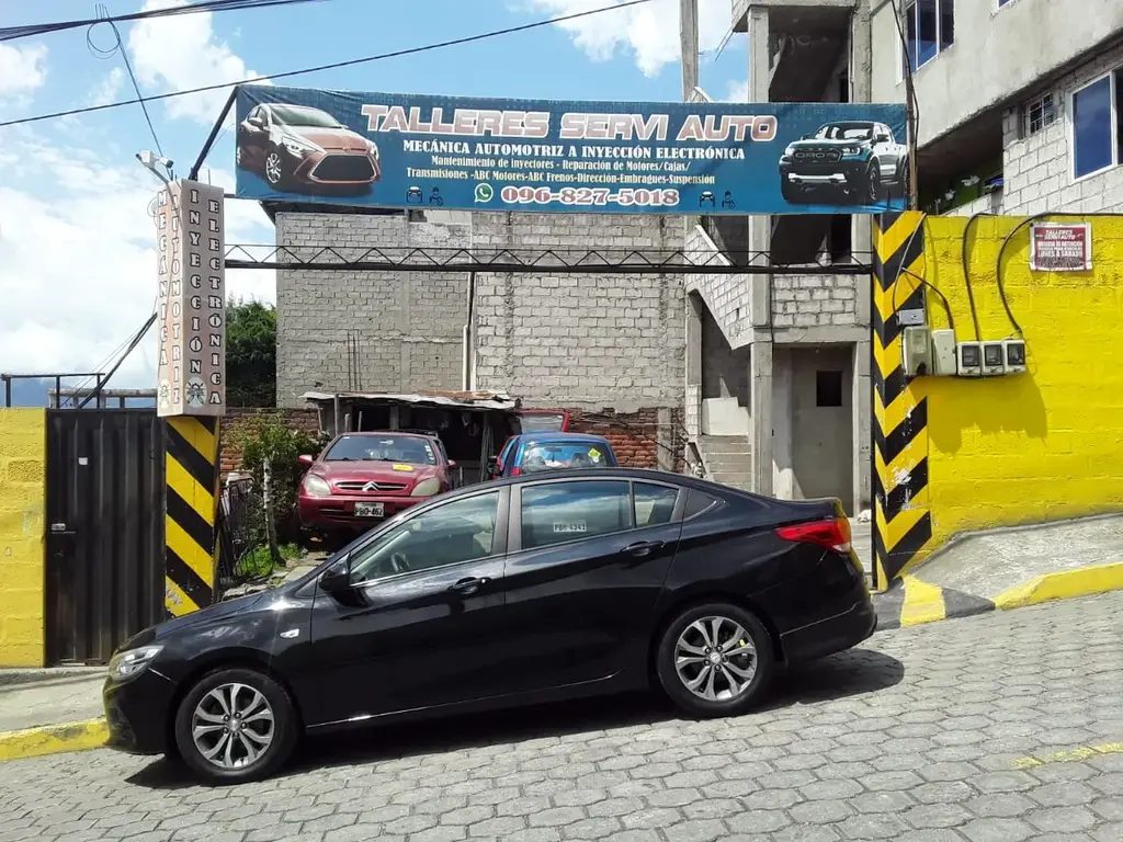 Entrada de Talleres Servi Auto en 2022, con el banner azul de la Av. La Cocha, Tréboles del Sur, sur de Quito